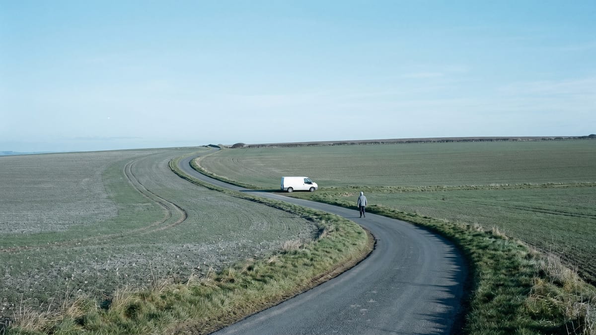 Strada di campagna che porta verso un crinale lontano, con un furgone e una figura piccola